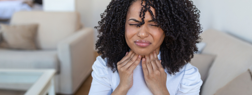 An image of a woman with post nasal drip holding her throat in discomfort.
