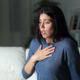 An image of a woman with heartburn holding her chest in pain.