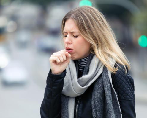 An image of a woman coughing into her fist,