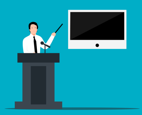 An image of a man standing at a podium and pointing at a screen.