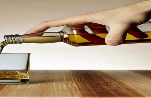 6 Shocking Reasons to Limit Alcohol Intake for Better Health in 2024 An image of a hand pouring alcohol beverage into a glass.