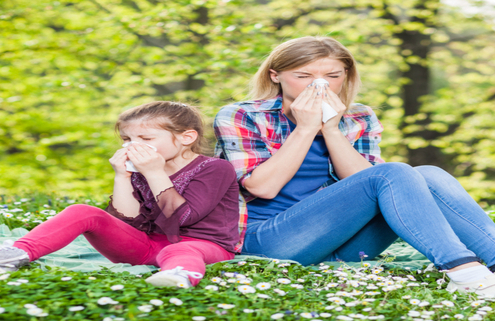 Mother and child with seasonal allergies blowing their noses.