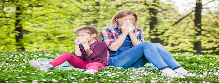 Mother and child with seasonal allergies blowing their noses.