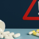 Contrave and Hydrocodone Drug Interactions Symbolized by 2 different types of pills with a warning sign between them.